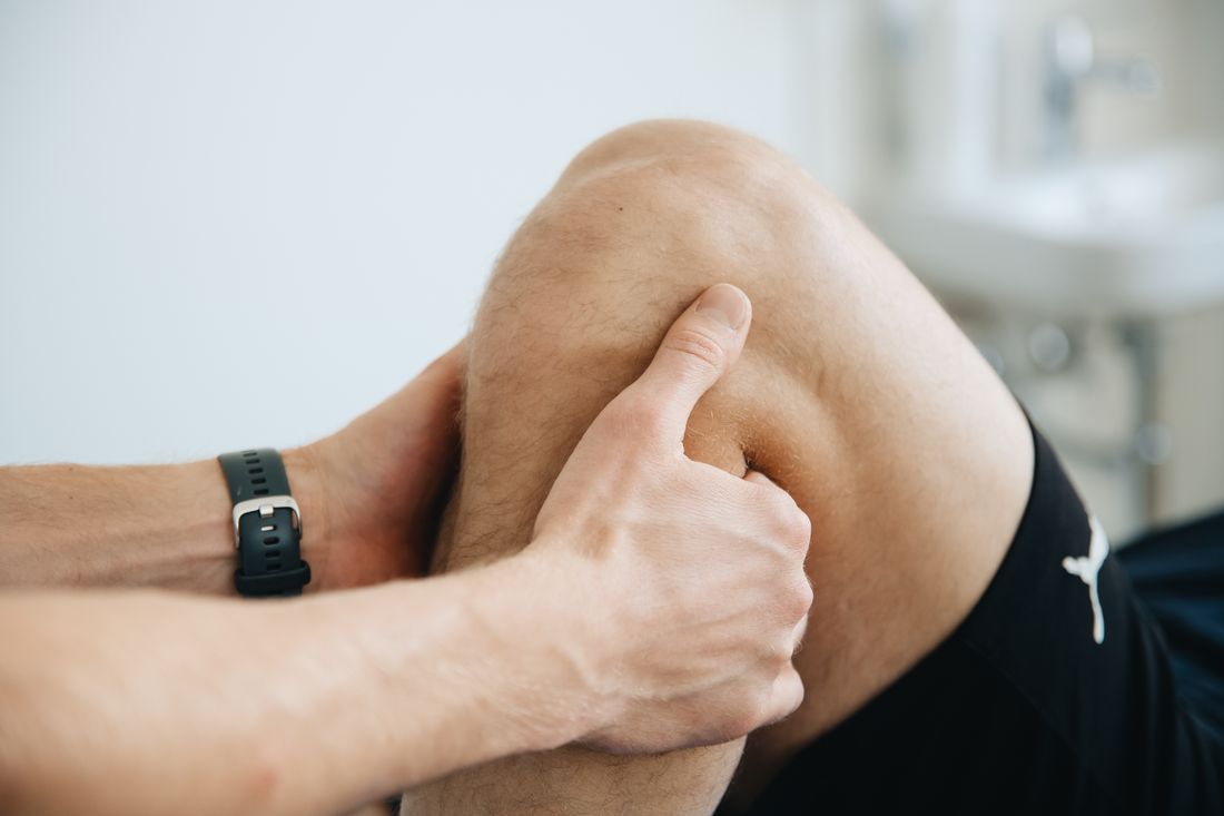 Fisioterapia do joelho: fisioterapeuta massageando o joelho e a perna do paciente