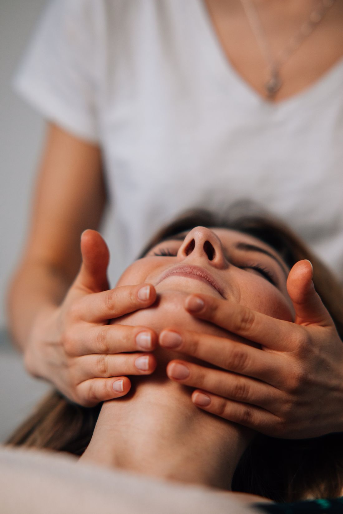 Profissional realizando terapia manual no rosto da paciente